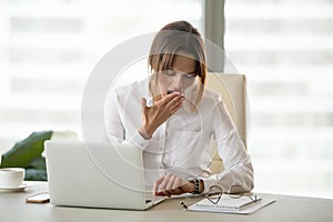 Exhausted female employee checking time on watch in office