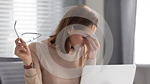 Exhausted female employee took off glasses, feeling pain in eyes.