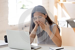 Exhausted female employee yawn feeling sleepy at workplace