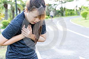 Exhausted female runner suffering painful angina pectoris or asthma breathing problems after training hard on summer. Running over