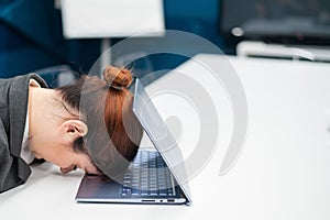 Exhausted Frustrated business woman put her head down on a notebook sitting at a desk. A female employee worked overtime