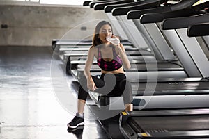 Exhausted girl drink water after run in gym