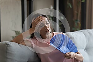 Exhausted indian female suffering from heat using hand fan