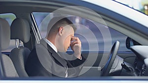 Exhausted male in formal suit sitting on driver seat, stressful life, overwork