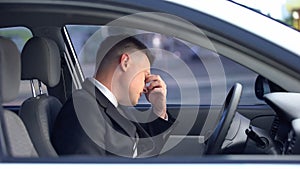 Exhausted male in formal suit sitting on driver seat, stressful life, overwork