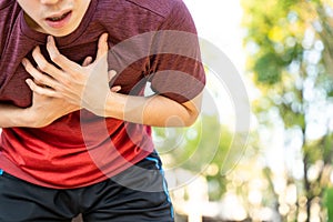 Exhausted male runner athlete suffering painful angina pectoris or asthma breathing problems while running in the park