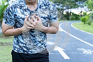 Exhausted male runner suffering painful angina pectoris or asthma breathing problems after running at the park. Sport and