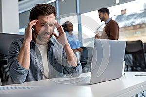 Exhausted man call center operator suffering headache at workplace