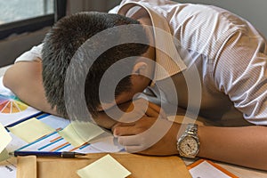 Exhausted man fall asleep on unorganized table with documents, sticky note