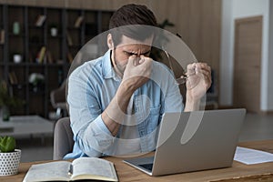 Exhausted man suffer from dizziness working on laptop