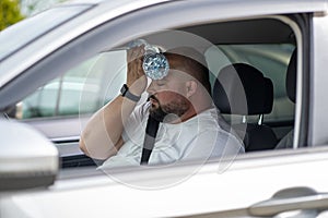 Exhausted man suffer from hot inside car with broken air conditioner put bottle of water to forehead