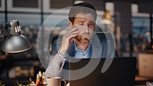 Exhausted man working laptop in late night office closeup. Tired businessman