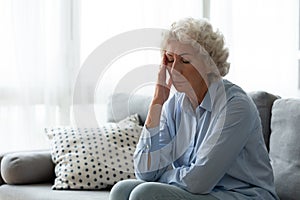 Exhausted mature woman suffering from headache indoors.
