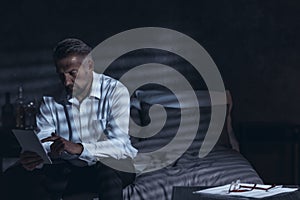 Exhausted middle-aged male sitting on a bed in a hotel room at n