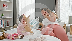 Exhausted mum and child find relaxation in play, sitting together on bedroom bed, toys scattered around, a cozy indoor expression