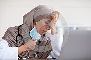 Exhausted muslim lady doctor removing protective face mask