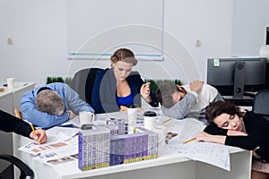 Exhausted office workers resting on their workplace, while havin