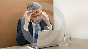 exhausted overworked businessman has headache in office. overworked businessman