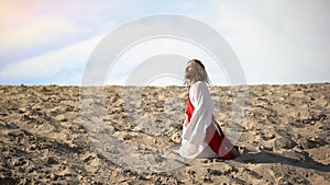 Exhausted pilgrim kneeing from exhaustion, lost in desert and life, concept photo