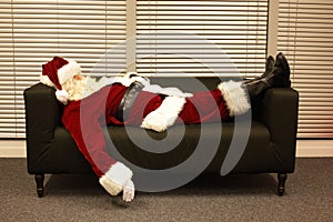 Exhausted santa claus sleeping on sofa