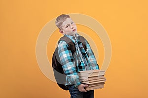 Exhausted schoolboy with backpack holding heap of books