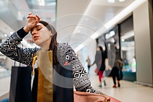 Exhausted shoppingholic woman in shopping mall.Buying in designer store.Wardrobe sale shopping.Hoby buyer.Weakness for clothes.