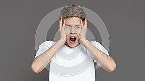 Exhausted teen boy shouting in panic, grey background