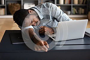 Exhausted tired African American businessman lying on desk and sleeping