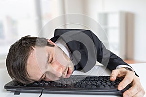 Exhausted or tired businessman is sleeping on keyboard in office photo