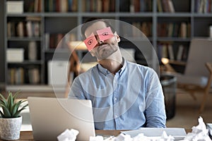 Exhausted tired businessman with stickers on eyes sleeping at workplace