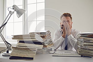 Exhausted tired worker at the workplace covered his face with his hands in the office photo