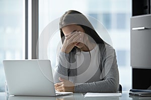 Exhausted tired young businesswoman massaging eyelids, feeling eyestrain photo