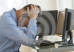 Exhausted Trader With Head In Hands Leaning At Computer Desk