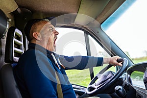 Exhausted truck driver yawning in his van.