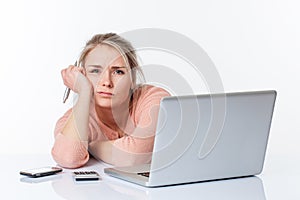 Exhausted unhappy blond girl leaning on her white sparse desk