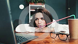 Exhausted woman drink coffee in office on table. Overtaxed concept. Worker drinks coffee from many straw. High quality