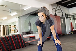 Exhausted Woman Leaning On Knees In Gym