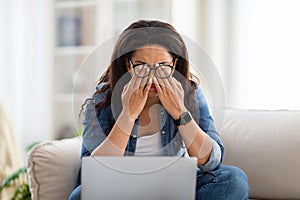 Exhausted Woman Sitting on Couch Covering Face With Hands