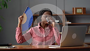 Exhausted woman suffer nervous breakdown or heat stroke at work use fan for fresh air drink water