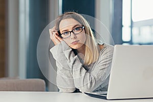 Exhausted woman at work yawns from painful sensations caused by wrong posture, sedentary work, long sitting at a laptop fibromyalg