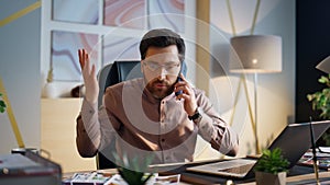 Exhausted worker talking smartphone worried profit loss at office close up.