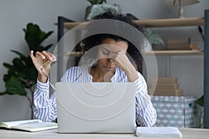 Tired African American woman worker suffer from headache photo