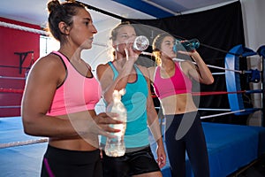 Exhausted young athletes drinking water by boxing ring