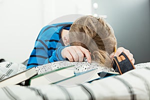 Exhausted young boy asleep on his text books