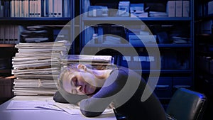 Exhausted young business woman office employee at the desk working late at night overloaded with paperwork. Female