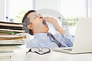 Exhausted young businessman yawning at work