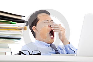 Exhausted young businessman yawning at work