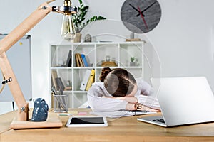 Exhausted young businesswoman sleeping at her desk at office in front of