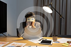 Exhausted young Caucasian man worker have sticker pads on eyes sleeping near computer in office. Tired millennial male employee