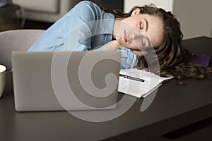 Exhausted young freelance professional girl falling asleep at work desk